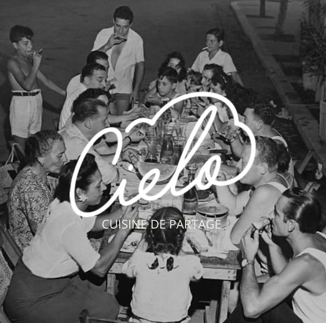 Photo ancienne en noir et blanc d'une grande tablée familiale, avec le logo Cielo, cuisine de partage